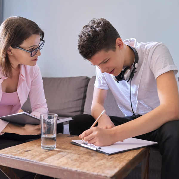 A college student sat on a sofa taking part in a therapy session with a Counsellor