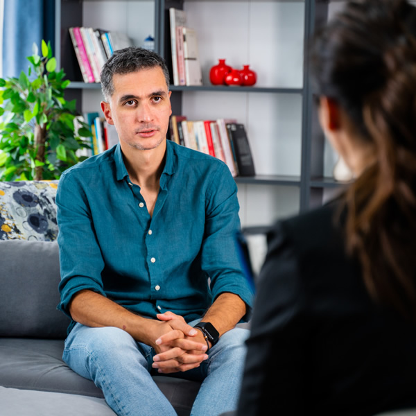 Man sat on a sofa receiving the benefits of counselling from a Therapist