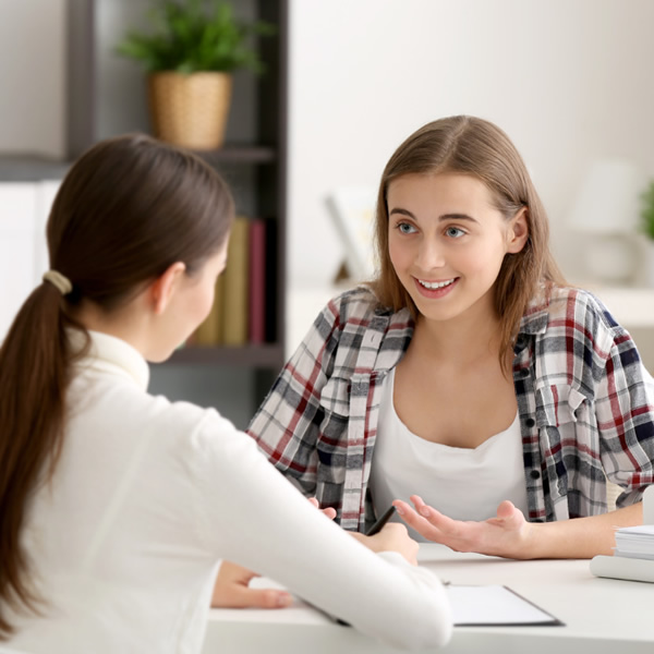 Young person sat on a chair in a counselling session with a Therapist